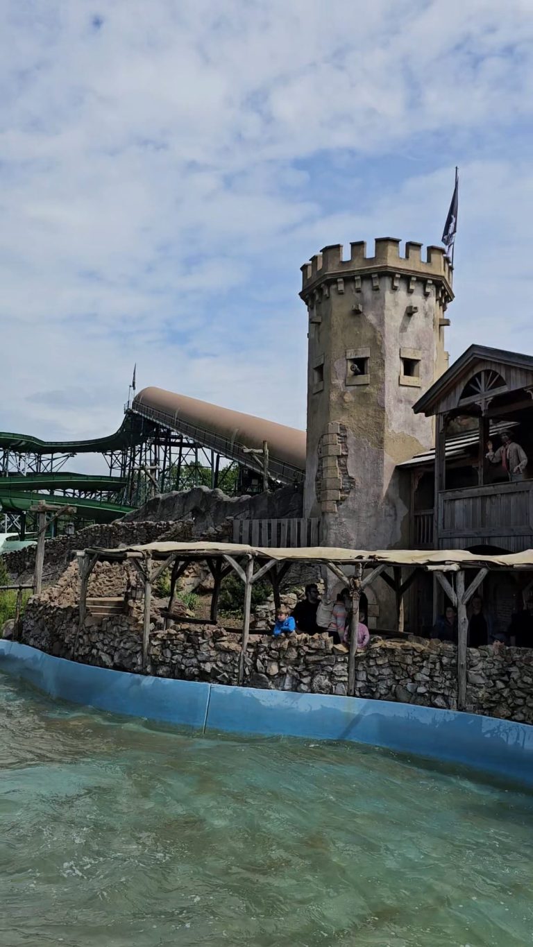 Wasserbahn/Rafting Burgartige Struktur mit Turm am Wasser, umgeben von Rutschen und Wasserattraktionen.